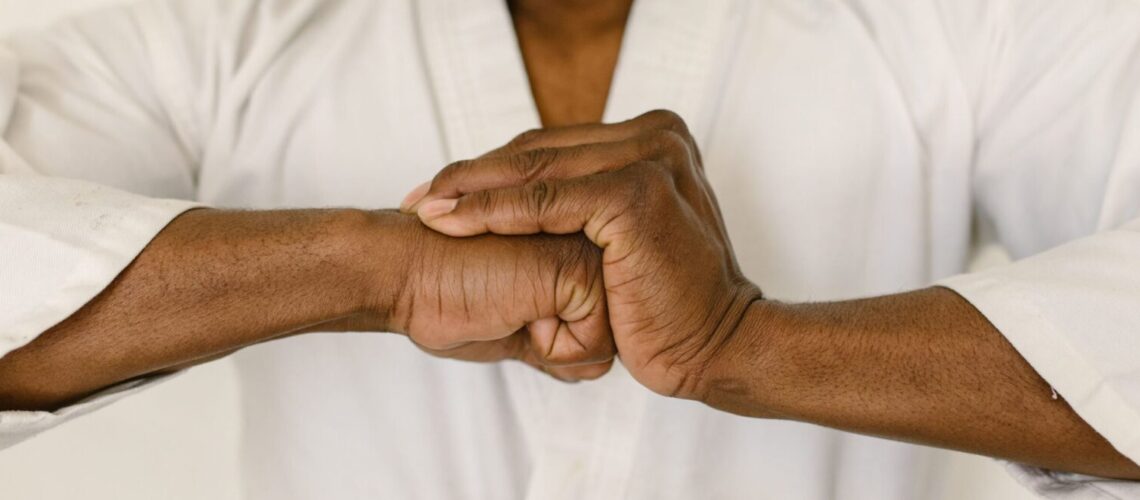Close-up of a martial artist's hands clasped in a traditional martial arts gesture.