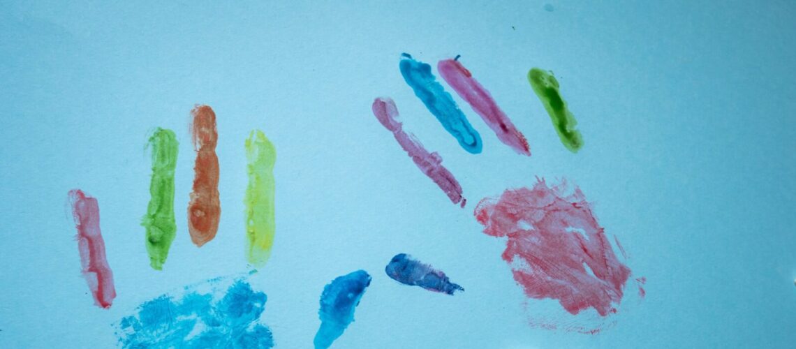 Colorful child handprints and autism text on a blue background, promoting awareness.